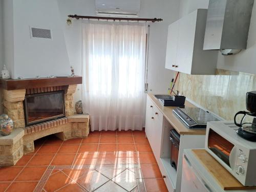 a kitchen with a fireplace and white cabinets at Casa Azélia e Albino in Aves