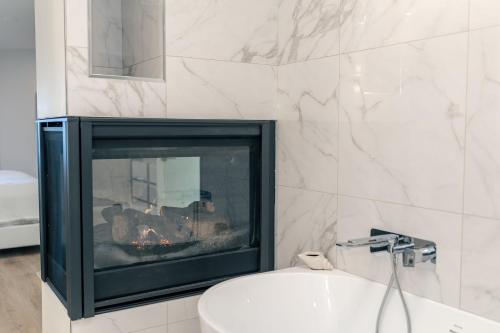 Nanoose BayにあるHigh Tide Suite - New Bright Oceanfront Escape with Spa-like Bathのトイレと暖炉のある浴室の暖炉