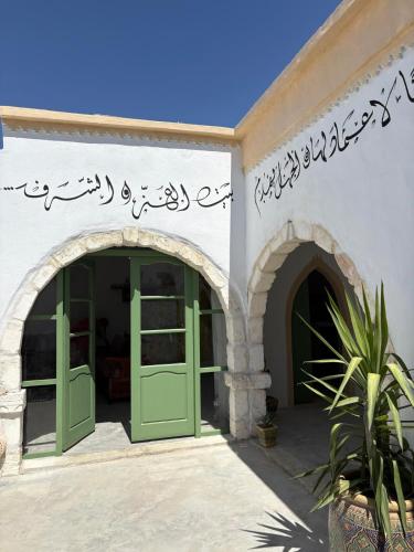 an entrance to a building with green doors at Dar El Ayla, maison djerbienne Djerbahood in Erriadh