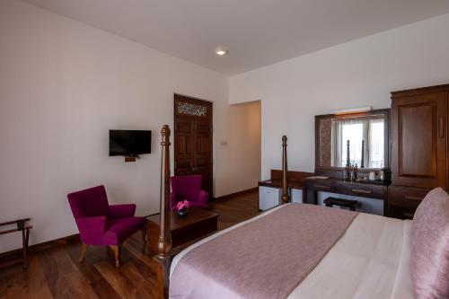a bedroom with a bed and a desk and purple chairs at Villa 46 in Hikkaduwa
