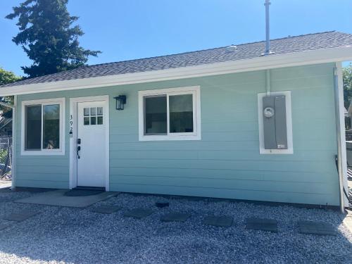 ein grünes Haus mit einer weißen Tür und Fenstern in der Unterkunft Newer Cozy Guest Cottage with Saltwater Spa! in Weed