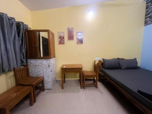 a bedroom with a bed and a chair and a table at Mogambo Hostel and Stays in Vagator