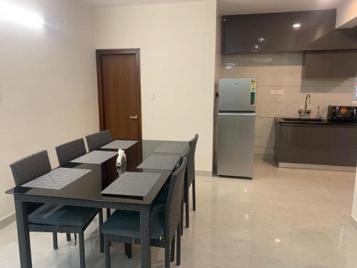 a kitchen with a table and chairs and a refrigerator at DeVerveil Mysore in Mysore