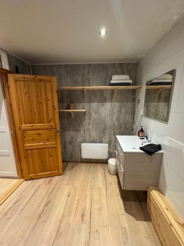 a bathroom with a wooden door and a sink at The Crush in Ersfjordbotn