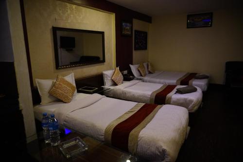 a hotel room with three beds and a mirror at Hotel Shree Tara in Kathmandu