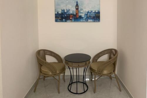 two chairs and a table in a room with a picture at DeVerveil Mysore in Mysore