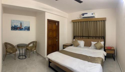a bedroom with a bed and a table and chairs at DeVerveil Mysore in Mysore