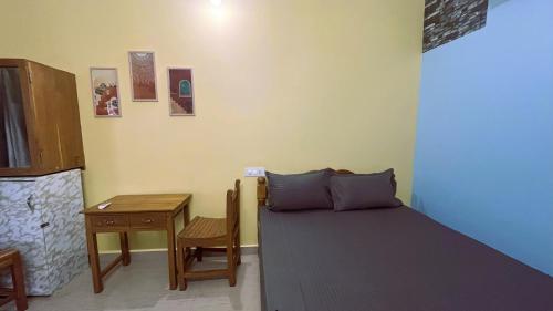 a bedroom with a bed and a table and a desk at Mogambo Hostel and Stays in Vagator