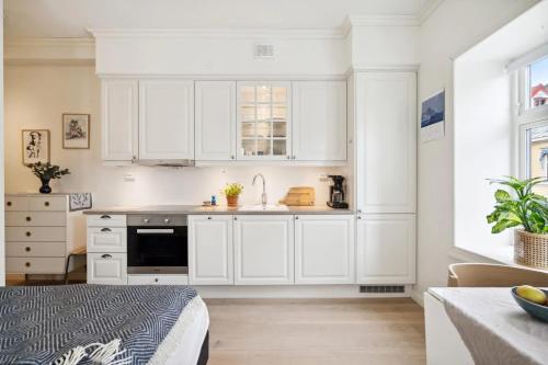 a white kitchen with white cabinets and a sink at Central and modern in Tromsø
