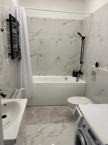 a white bathroom with a tub and a toilet and a sink at Dream Apartment in Liepāja