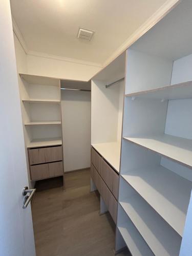 a walk in closet with white shelves and a door at Casa elegante privada y moderna in Coquimbo