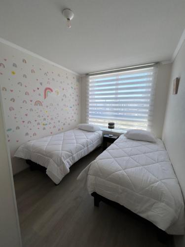 a bedroom with two beds and a window with a rainbow mural at Casa elegante privada y moderna in Coquimbo