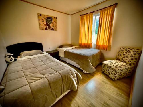 a bedroom with two beds and a chair and a window at Cabin in Puerto Godoy - Maullin in Maullín