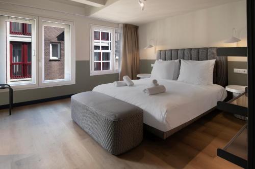 a bedroom with a large white bed and two windows at Hotel Zeedijk City Centre in Amsterdam