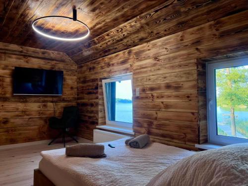 a bedroom with wooden walls and a bed and a window at Glamping "Letnisko WISOLA" in Ciemnik