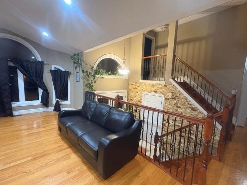 a living room with a leather couch and a staircase at Cozy and quiet room close to riverside in Windsor