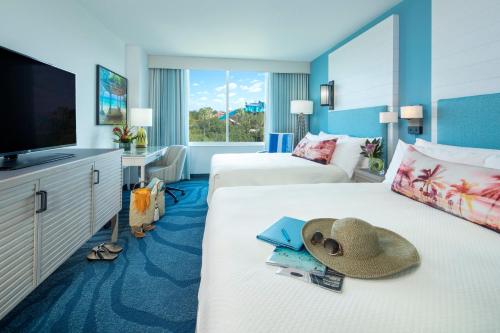 Habitación de hotel con 2 camas con sombrero y TV en Universal's Loews Sapphire Falls Resort, en Orlando