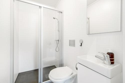 a white bathroom with a toilet and a shower at Stylish Coastal House with Stunning Ocean View in Borhaug