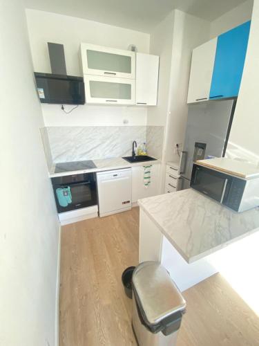 a small kitchen with white cabinets and a stool at Appartement T2 cosy au calme in Épinay-sur-Orge