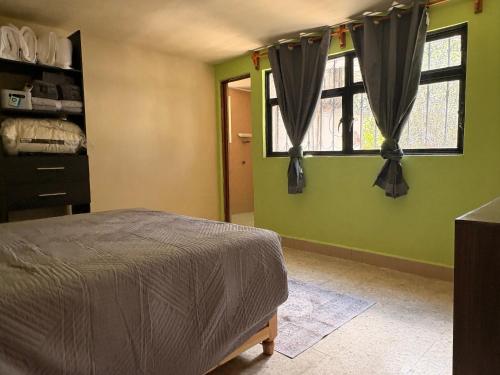 a bedroom with green walls and a bed and windows at Rancho Santa Mónica 