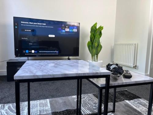 a living room with a table with a large screen tv at Home In Maidstone in Maidstone