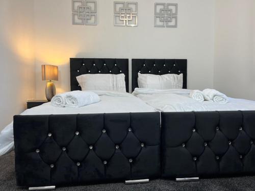 a large black bed with white sheets and pillows at Home In Maidstone in Maidstone