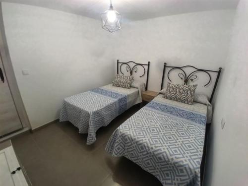 a room with two beds and a pendant light at Sweet hause carril 23 in Caravaca de la Cruz