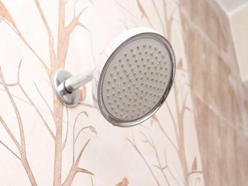a shower head on a wall with a tree mural at Starlight Hotels Chennai Trade Center in Chennai