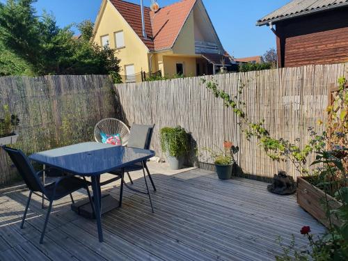 eine Terrasse mit einem blauen Tisch und Stühlen vor einem Zaun in der Unterkunft Studio Les Deux Grenouilles 5mn de Colmar in Herrlisheim-près-Colmar