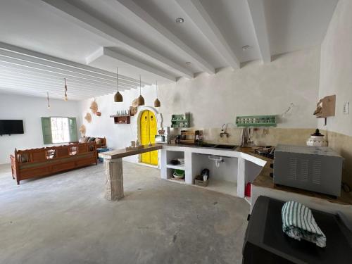 a large kitchen with a counter and a yellow door at Dar El Ayla, maison djerbienne Djerbahood in Erriadh