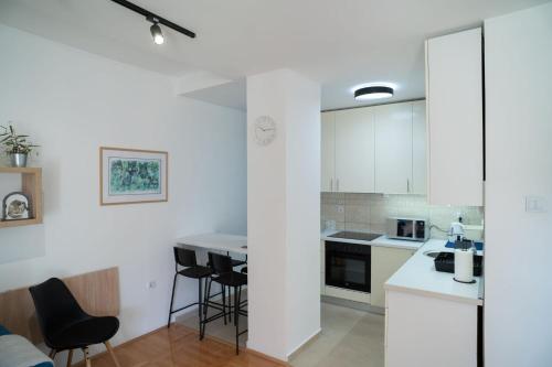 a kitchen with white cabinets and black chairs at WellNest Niš in Niš
