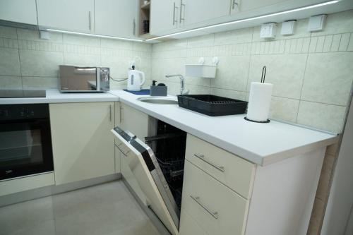 a white kitchen with a sink and a microwave at WellNest Niš in Niš