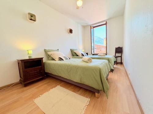 a bedroom with two beds and a television and a window at L'Éclat des cimes I 105 m2 & centre ville in Le Bourg d'oisans