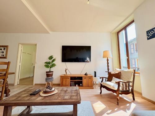 a living room with a table and a tv at L'Éclat des cimes I 105 m2 & centre ville in Le Bourg d'oisans