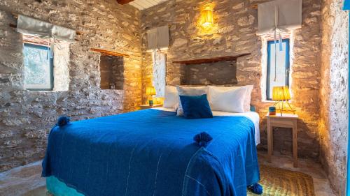 a bedroom with a blue bed in a stone wall at Atlantis 12, Maison d'hôtes et d'art in Essaouira