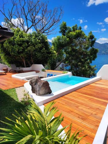 a pool on a deck with a view of the water at Lakefront Villa with Beach Access & Infinity Pool in San Pedro La Laguna