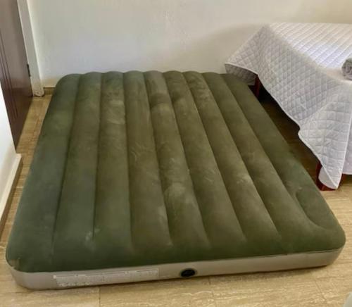 a green mattress on the floor next to a bed at Mi Refugio Apartment in Río San Juan
