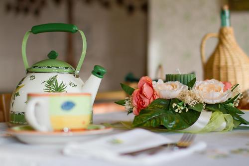 uma chaleira e um prato com flores sobre uma mesa em Casa Krajnova em Oblizza