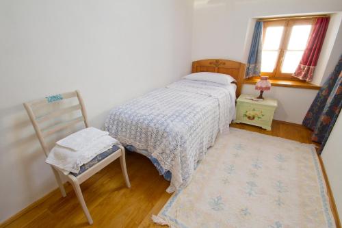 a bedroom with a bed and a chair and a window at Casa Krajnova in Oblizza