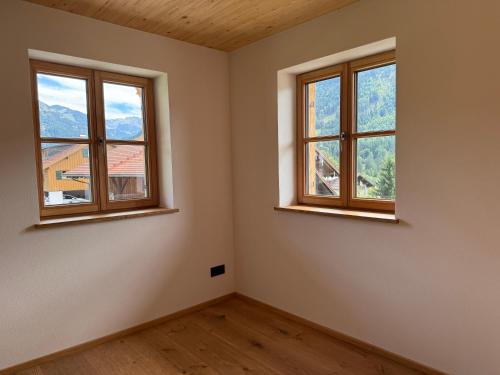 an empty room with two windows in a house at DAS BISCHOF - 5 exklusive Ferienwohnungen mit privaten Zirbensaunen in Bad Hindelang