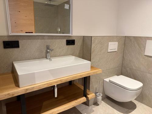a bathroom with a sink and a toilet at DAS BISCHOF - 5 exklusive Ferienwohnungen mit privaten Zirbensaunen in Bad Hindelang