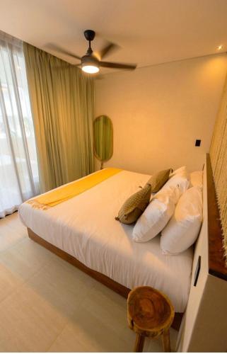 a bedroom with a bed with white sheets and pillows at Tulum Getaway with Jacuzzi & Pools in Tulum