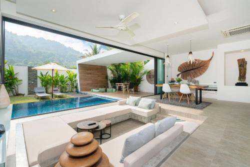 an open living room with a swimming pool and a house at Eden Escape Naiyang Beach in Phuket