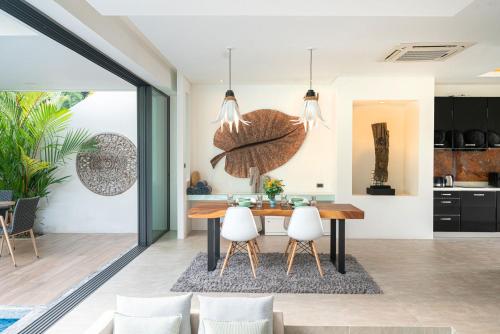 a kitchen and dining room with a wooden table and white chairs at Eden Escape Naiyang Beach in Phuket