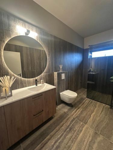a bathroom with a sink and a toilet and a mirror at Golden circle luxury villa in Grímsnes og Grafningshreppur