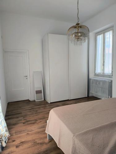 a white bedroom with a bed and a chandelier at Appartamento Madonna 31 in Rho