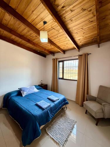 a bedroom with a blue bed and a chair at Los Leños in Tafí del Valle