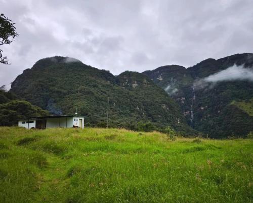 a house in a field with mountains in the background at Choachi casa colibri in Choachí