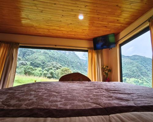 a bedroom with a bed and a large window at Choachi casa colibri in Choachí
