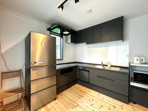 a kitchen with a stainless steel refrigerator and wooden floors at 楽宿箱根 Rakuyado Hakone in Hakone